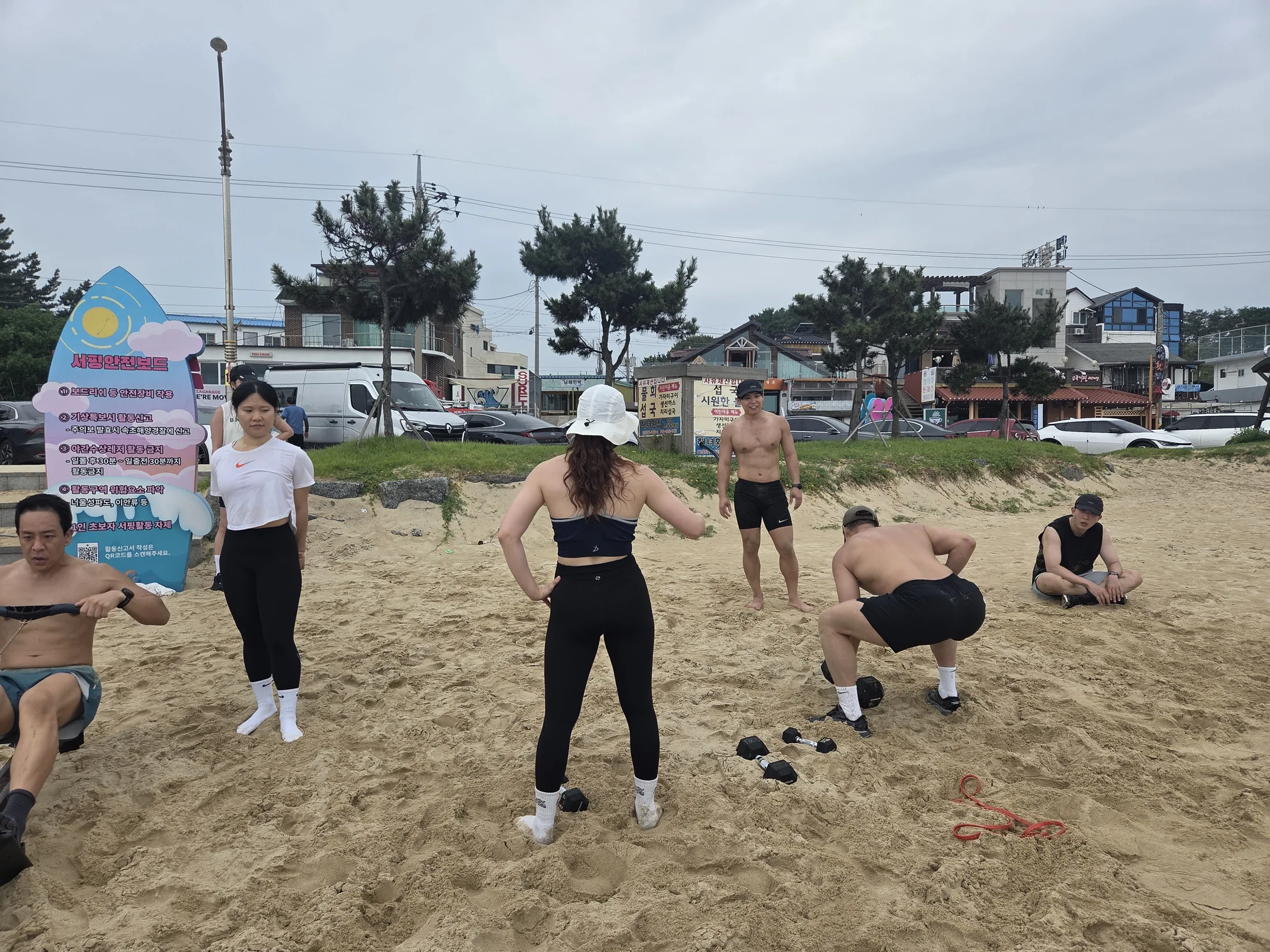 덤벨 동작과 로잉을 함께 수행하는 해변 WOD 참가자들